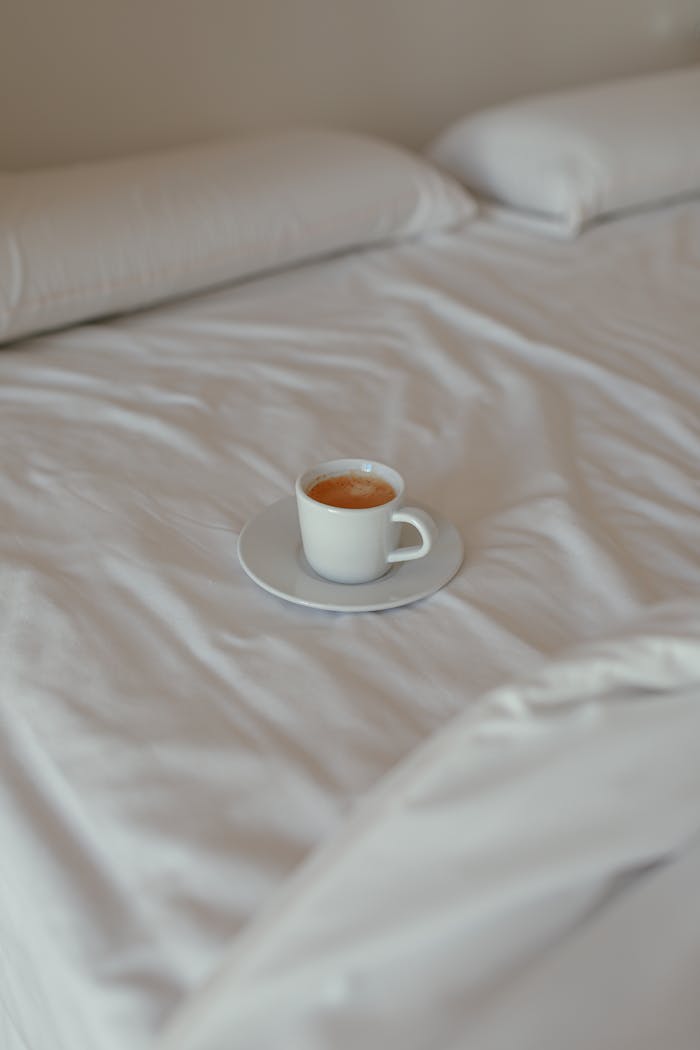 A warm cup of coffee on a neatly made bed, perfect for a tranquil morning moment.