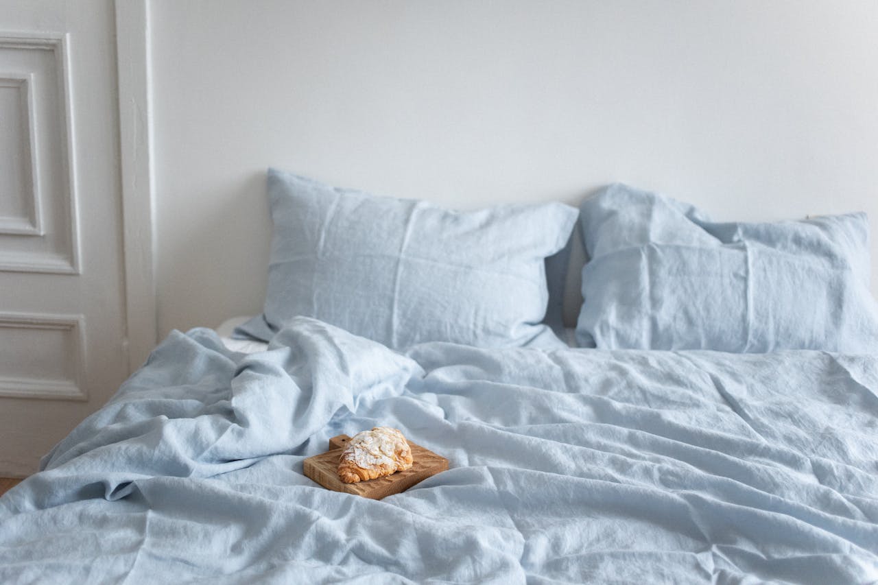 A tranquil bedroom scene featuring a croissant on a light blue bed, creating a cozy and inviting ambiance.